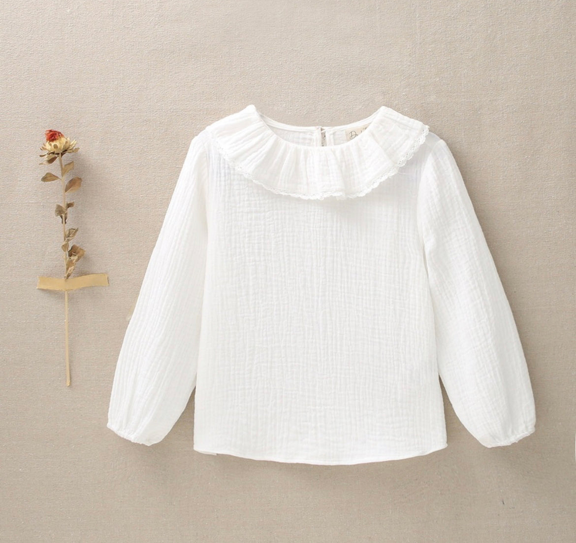 Blusa de niña con cuello de volante en muselina de color blanco